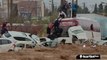 People climb onto vehicles tossed around by powerful floodwaters to escape drowning