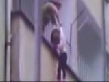 Una mujer descuelga a su hija por el balcón para recoger la ropa del tendedero