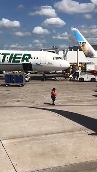 Elle danse entre les avions sur la piste de l'aéroport avec les bâtons de signalisation !