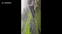 Trekker shows off terrifyingly slippery climb along cliff edge in west India