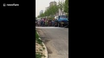 Bizarre moment moped riders patiently drive behind van spraying water in China