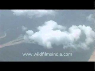 Flying over monsoon-filled river through cloudy skies, into Kathmandu airport