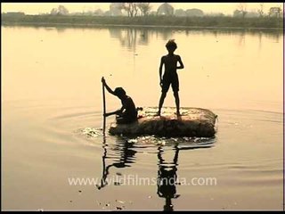 Rag pickers scavenger on raft made of sacking and polystyrene in Yamuna