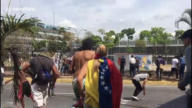 Protesters in Caracas throw stones at the National Guard motorcycle