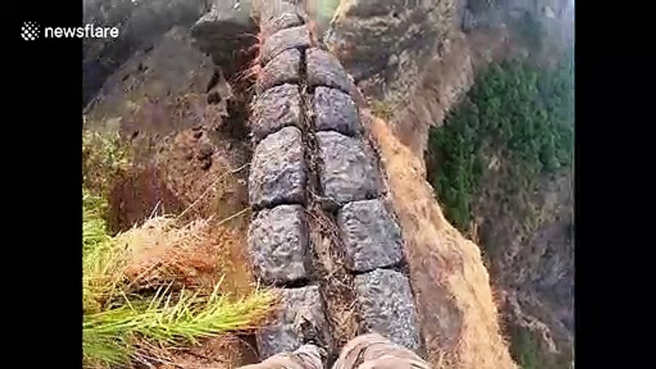 Trekker takes a high risk walk along edge of a mountain fort in central India