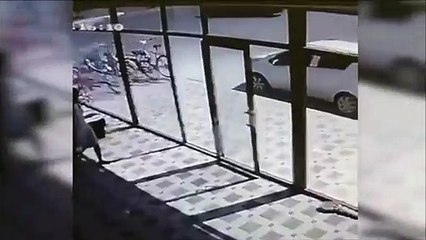 Une femme piégée par une porte vitrée