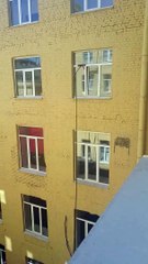 Un laveur de vitres utilise une brosse avec un très long manche