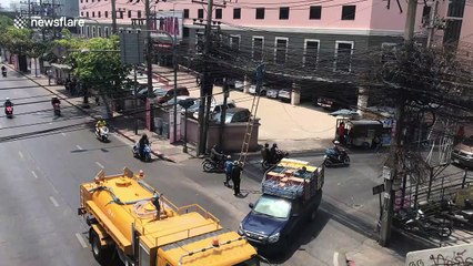 Health And Safety? Workers plant tall ladder In the middle of the road in Bangkok, Thailand