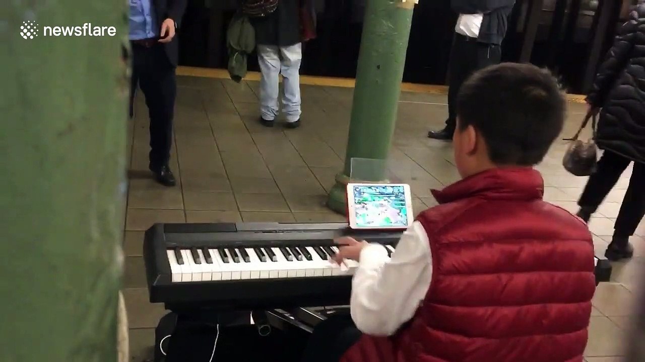 Child prodigy plays Mozart masterpiece while playing a computer game at the same time in New York, USA