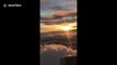 Destination heaven: Plane flies through layers of clouds in serene sunset
