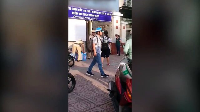 Hai chiến sỹ CSGT đứng trước cổng trường phát nước miễn phí cho thí sinh và phụ huynh ở Sài Gòn