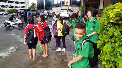 School children wade through water after flash floods in Bangkok
