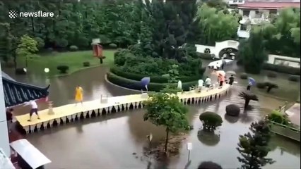 Teachers use tables to build bridge so students can walk across flooded courtyard in China