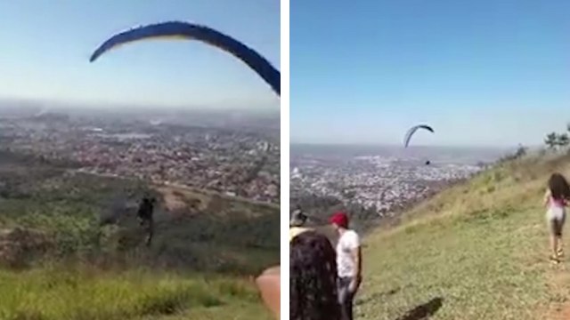 Un chien s'accroche à l'équipement d'un homme en parapente au moment du décollage