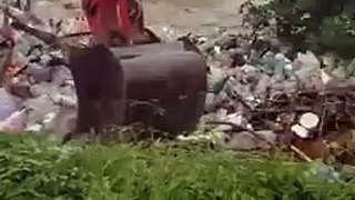 Un employé enlève les déchets accumulés au bord d’une rivière en les envoyant dans la rivière !