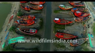 Beautiful red boats and green grass water way stationed under Dashmile Bridge, West Bengal, India. 4k Aerial stock footage