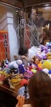 Un enfant entre dans un jeu de pinces pour voler les peluches à la fête foraine !