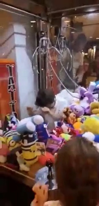 Un enfant entre dans un jeu de pinces pour voler les peluches à la fête foraine !
