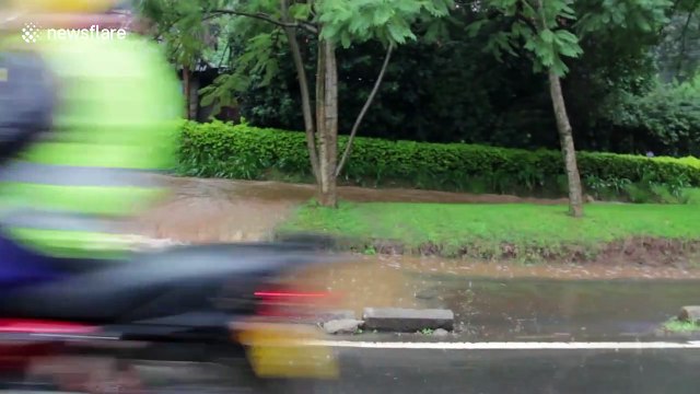 Pedestrians pay 10p to be taken across fast moving flood waters in Kenya
