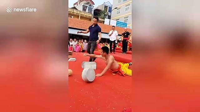 Vietnamese martial artist's arm resists concrete block being thrown onto it