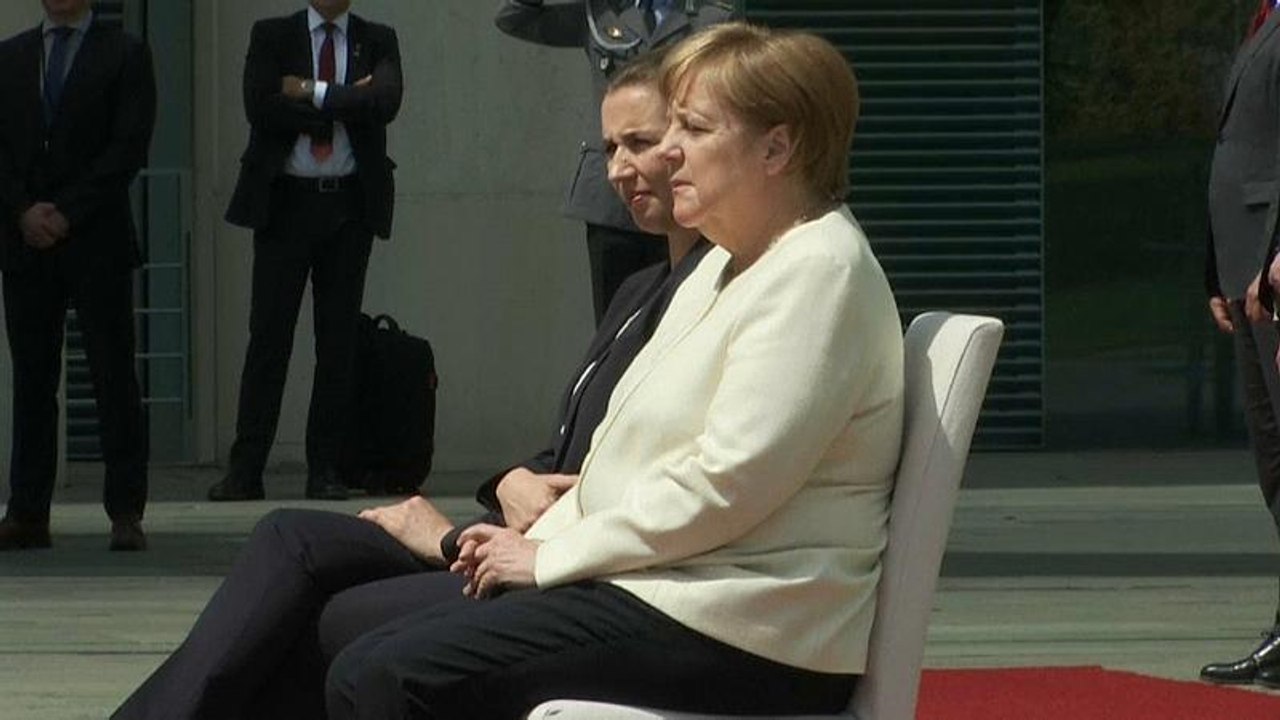 Merkel nach zitteranfall: militärische ehren im sitzen