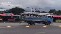 Reckless schoolboys climb onto roof of moving bus on busy road in Thailand