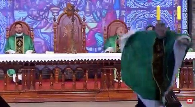 Une femme pousse violemment un prêtre de la scène et le fait tomber par terre