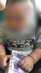 This baby boy is playing with money believed to have been laundered drug money.