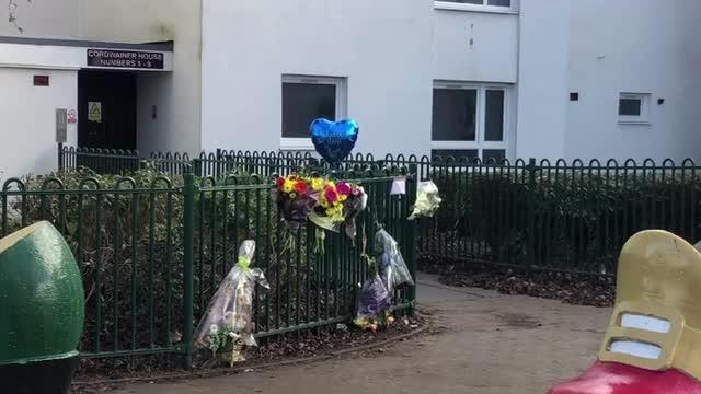 Seven bunches of flowers and a blue heart-shaped balloon have been left by the railings at the scene of a Northampton murder.