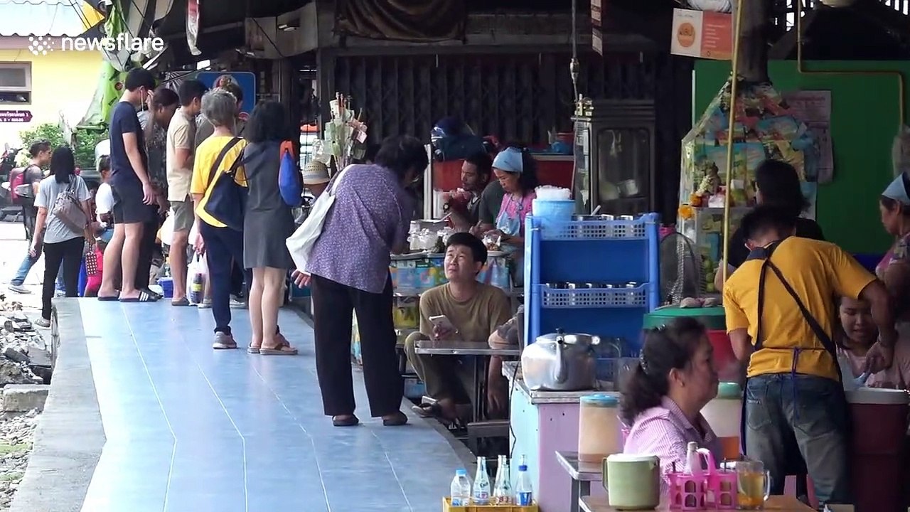 Locals eat at tables just inches from passing trains at Thai restaurant