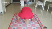 Elderly Chinese man headstands while practising calligraphy with his foot