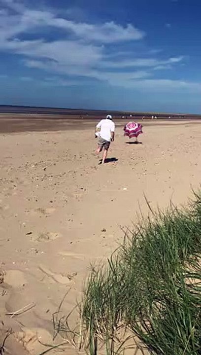 Ce touriste qui court derrière son parasol sur la plage...