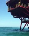 Une fille hésite avant de sauter dans la mer depuis une plateforme pétrolière