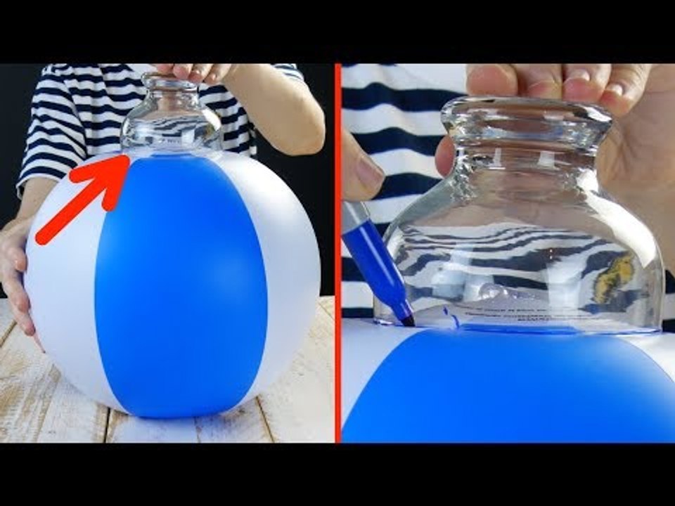 Cette femme presse un verre sur le ballon de plage pour...