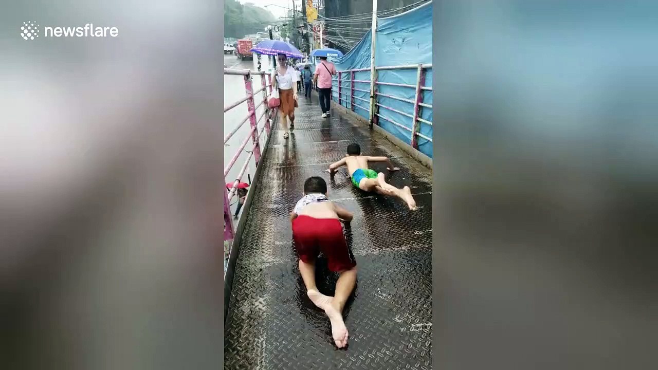 Children use pedestrian bridge as water slide during Philippines rain storm