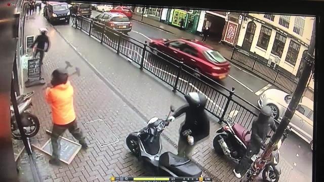 This shocking footage shows a salon worker fighting off a gang of moped riders with a shop sign - as they tried to smash into a jewellery shop with sledgehammers