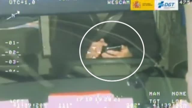 Un conductor juega con un cubo de colores mientras conduce