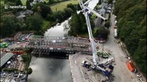 Drone footage shows footbridge being lifted into place over UK river