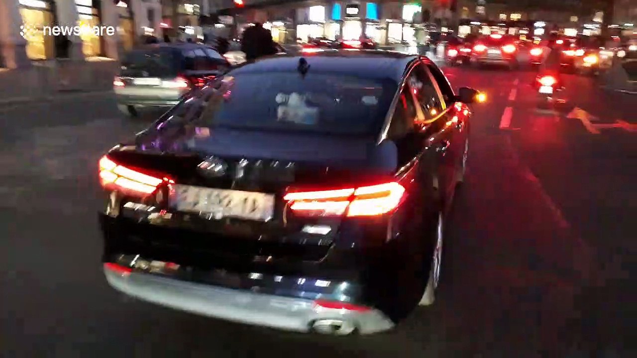 Man rides on electric scooter with dog between his legs on busy Paris roads