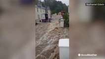 Floodwaters gush down road, sweeping away van