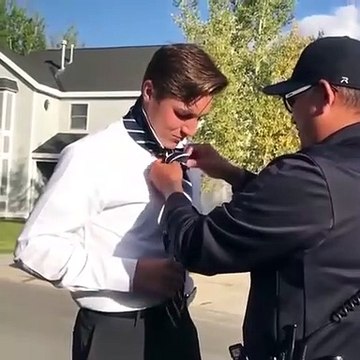 Un policier aide un jeune homme faire le nœud de sa cravate... Sympa