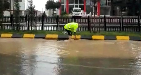Trafik polisi, ayakkabılarını çıkararak aşırı yağış nedeniyle tıkanan mazgalları temizledi