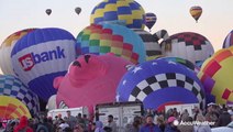 Hot air balloons of all colors, shapes, and sizes rise into the sky