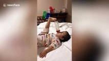 Hands-free! Ingenious baby uses TOE to hold milk bottle in place while feeding herself