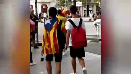Una chica con bandera de España en Passeig de Gràcia y  un hombre se la intenta quitar