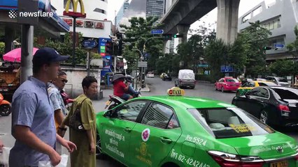 Thai man holds chair on head while sitting at back of motorcycle