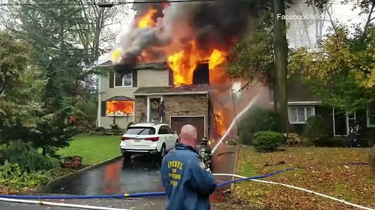 Firefighters battle flames at a home after a small plane crash