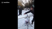 Good catch! Man throws a glass of beer using a snowboard and his friend successfully catches it
