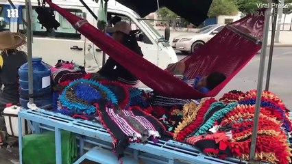 Toddler sleeps in hammock in back of his parent's motorcycle trailer