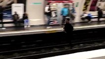 Un parisien court sur la voie du métro pendant qu'il se fait courser par un contrôleur